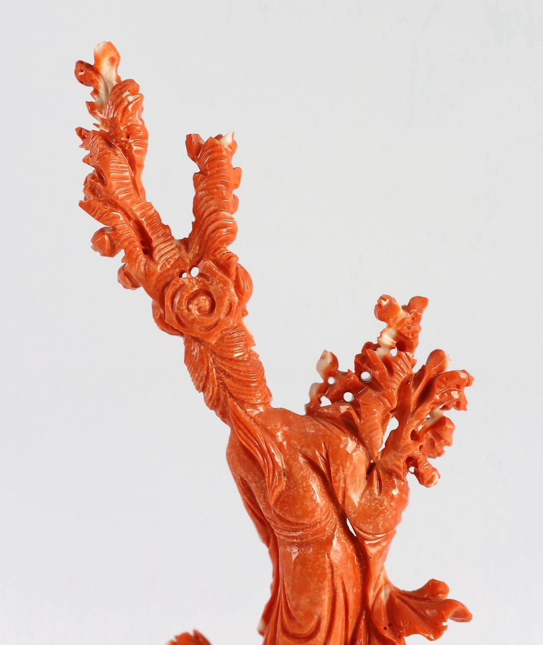 A Chinese carved coral figure of a flower fairy, 20th century, the carving 19cm high and 119g, wood stand